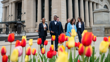Six students dressed in business attire walking and smiling outside the Senate of Canada Building, with tulips in the foreground.