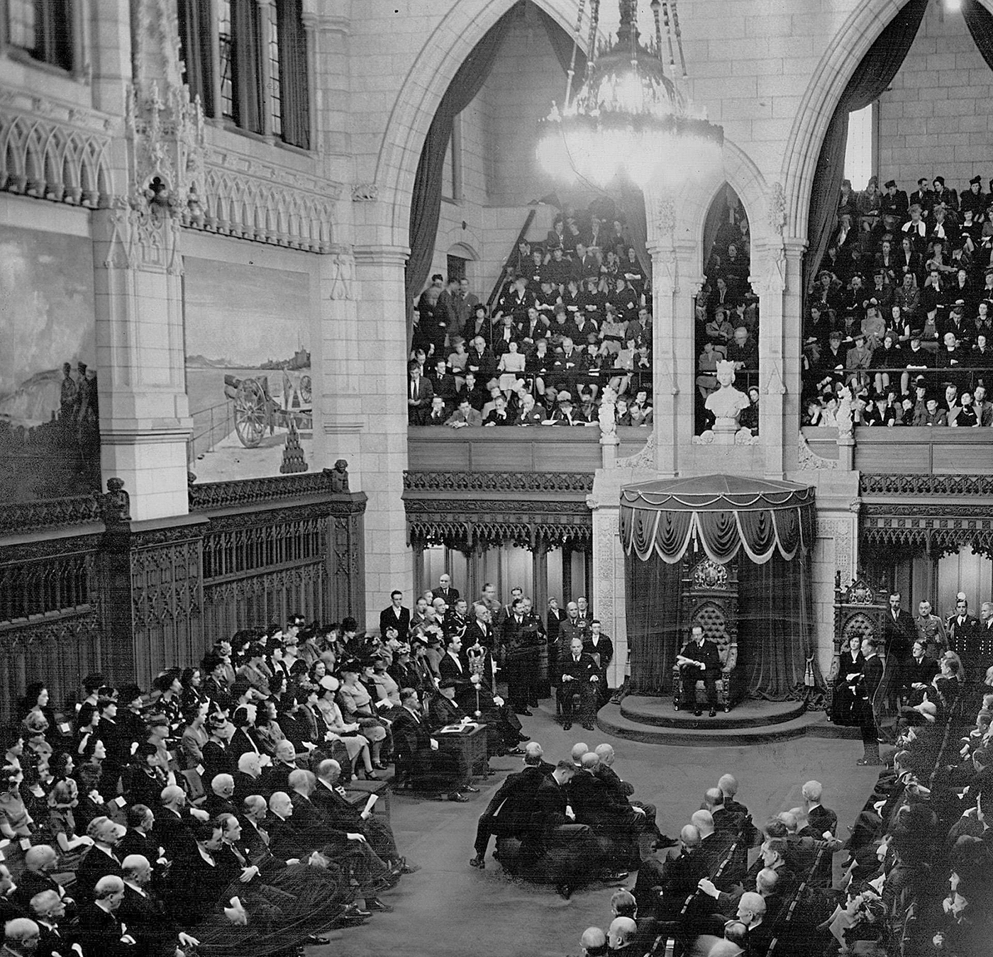 Governor General Viscount Alexander reads the Speech from the Throne during the opening of the fifth session of Canada’s 20th Parliament in 1949. Directly in front of him, Canada’s Supreme Court judges sit on the <a href='https://sencanada.ca/en/sencaplus/how-why/how-a-venerable-senate-icon-got-the-sack/' target='_blank'>woolsack</a>, a large stuffed cushion that served for decades as a ceremonial seat. The woolsack was retired and put into storage after this session. (Photo credit: Toronto Public Library)