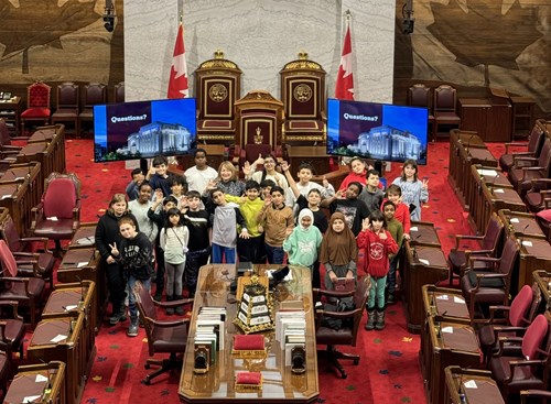 Group of students with Senator Donna Dasko in the Red Chamber in front of the thrones.
