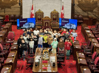 Group of students with Senator Donna Dasko in the Red Chamber in front of the thrones.