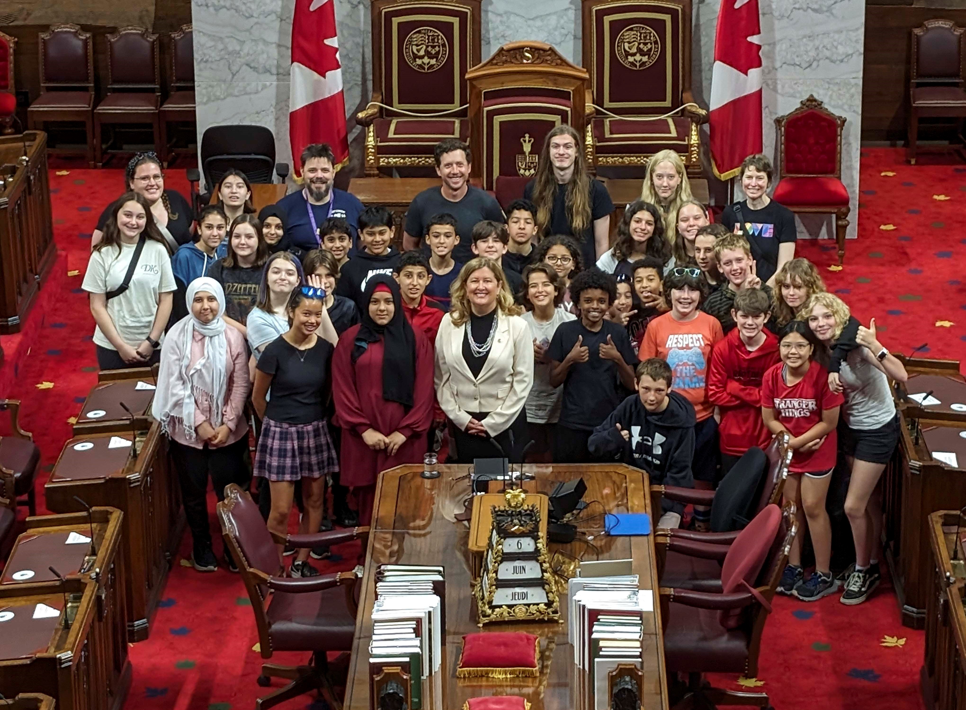 La sénatrice Krista Ross pose avec des élèves de l’école publique D. Roy Kennedy dans la Chambre rouge.