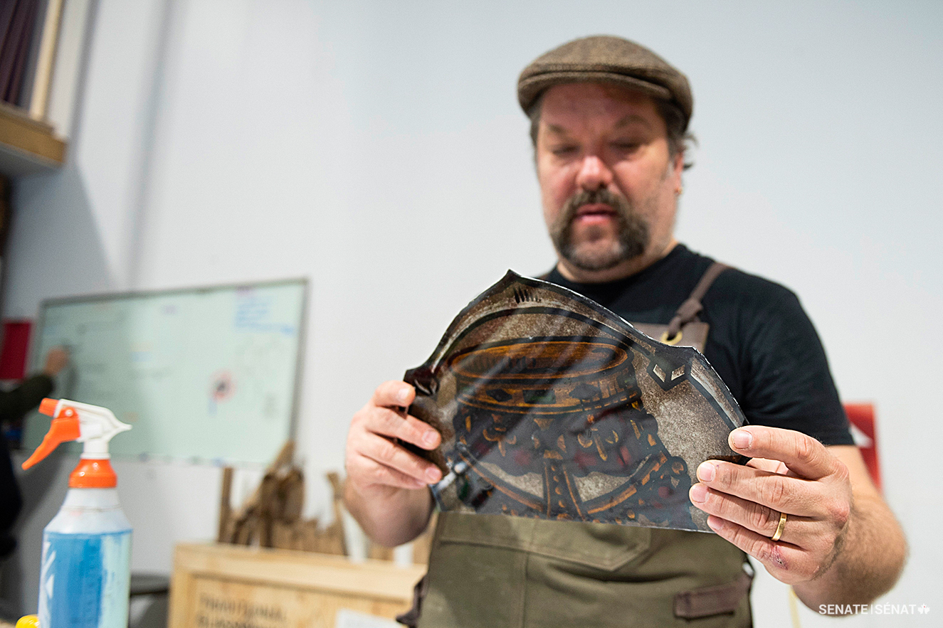 Conservator Tristan Adams reinforces a thin piece of glass with a clear, non-reflective backplate.