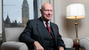 Senator Jean-Guy Dagenais sits in his office with a view of the Peace Tower in the background.