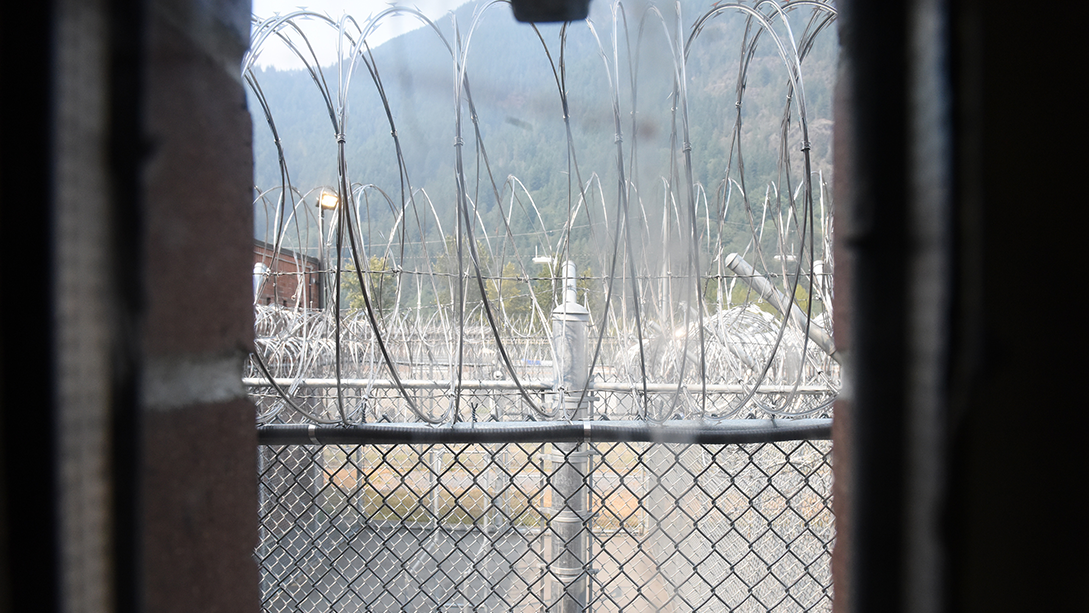 Vue sur des clôtures à mailles métalliques couronnées de barbelés depuis une cellule d’isolement à la prison d’Agassiz, en Colombie-Britannique.