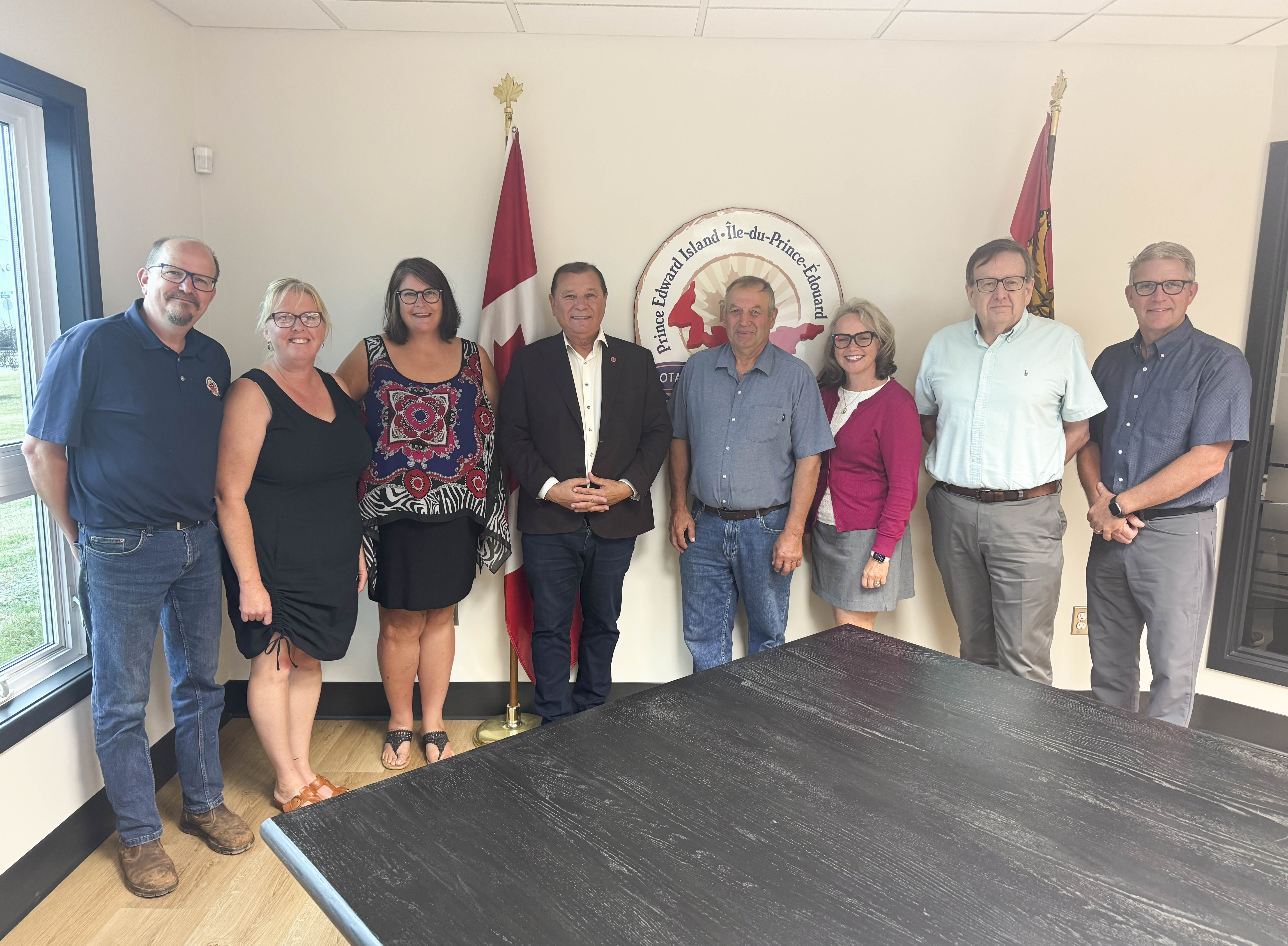 A group of men and women pose together in a meeting room.