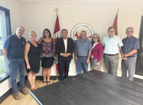 A group of men and women pose together in a meeting room. 