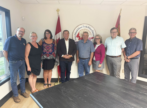 A group of men and women pose together in a meeting room. 