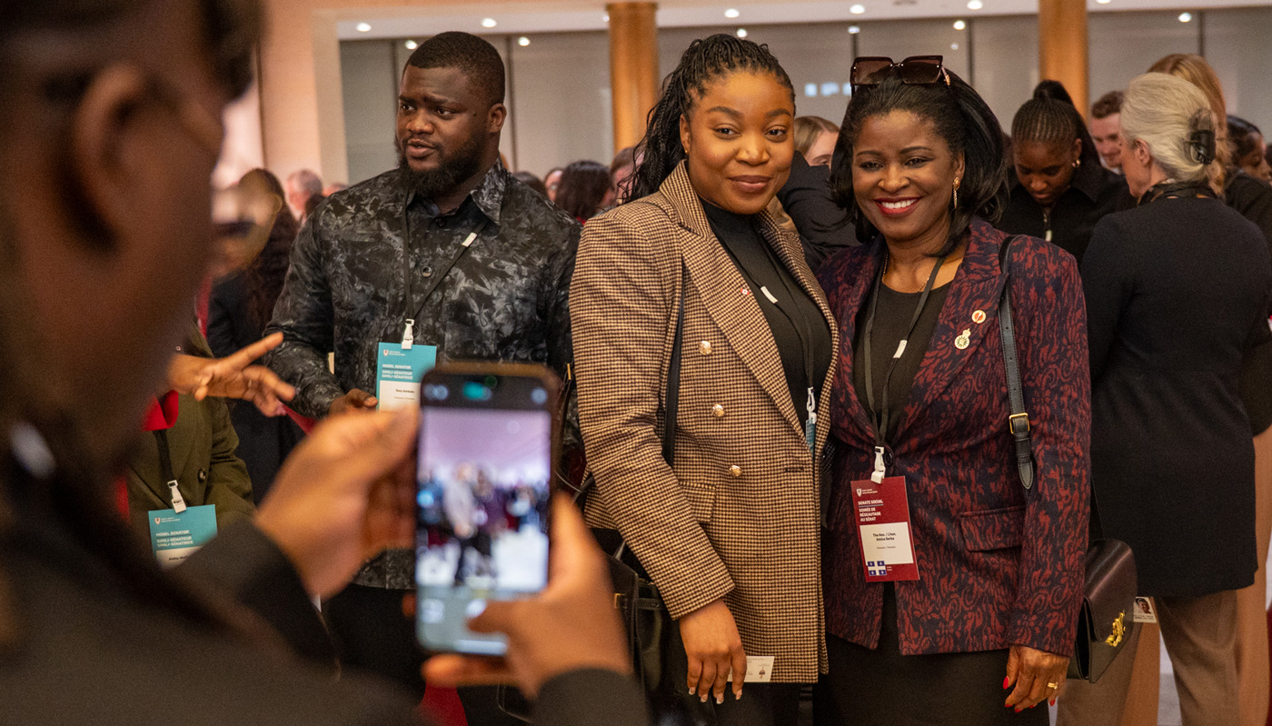 Two women pose together in a crowded room.