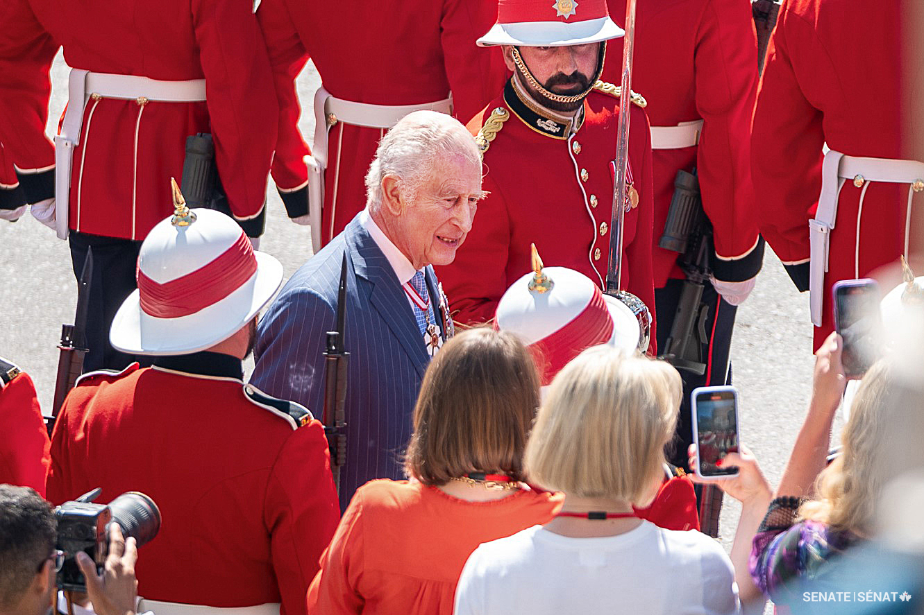 The King is swallowed up in a sea of red as he inspects members of the Royal Canadian Regiment, who provided his guard of honour.