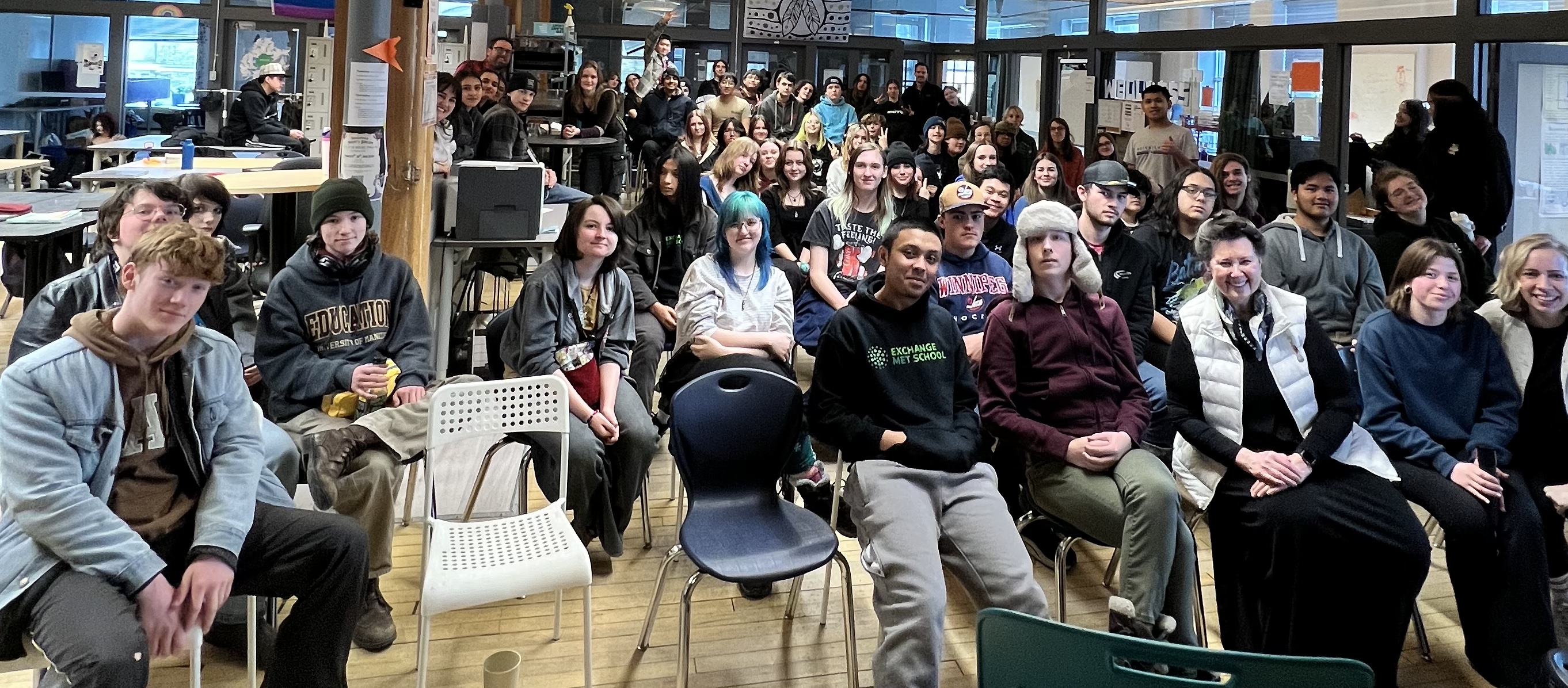 Un groupe de personnes assises dans une grande pièce sourit pour une photo.