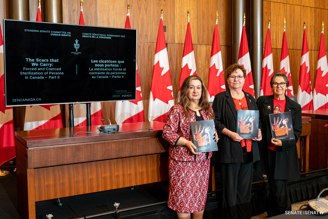 Les sénatrices Salma Ataullahjan, présidente du comité, Yvonne Boyer et Kim Pate tiennent une copie du deuxième rapport sur la stérilisation forcée et contrainte du Comité sénatorial des droits de la personne rendu public le 14 juillet 2022.