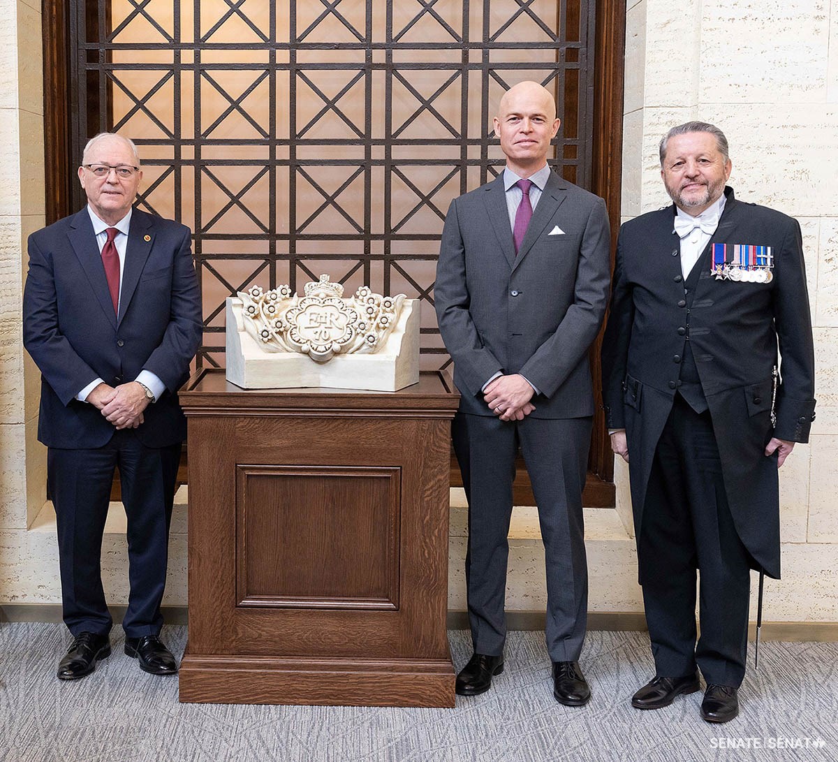 From left to right, Senate Speaker George J. Furey, Dominion Sculptor John-Philippe Smith and Usher of the Black Rod J. Greg Peters unveil the maquette in a ceremony at the Senate of Canada Building in December 2022.