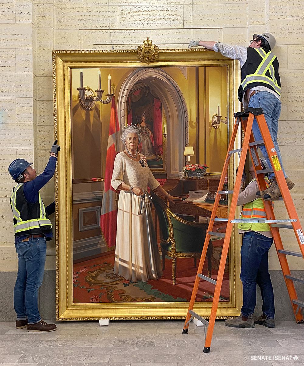 Des restaurateurs d’œuvres d’art de Legris Conservation, à Ottawa, s’affairent à accrocher le portrait du jubilé de diamant dans l’entrée principale de l’édifice du Sénat du Canada (janvier 2025).
