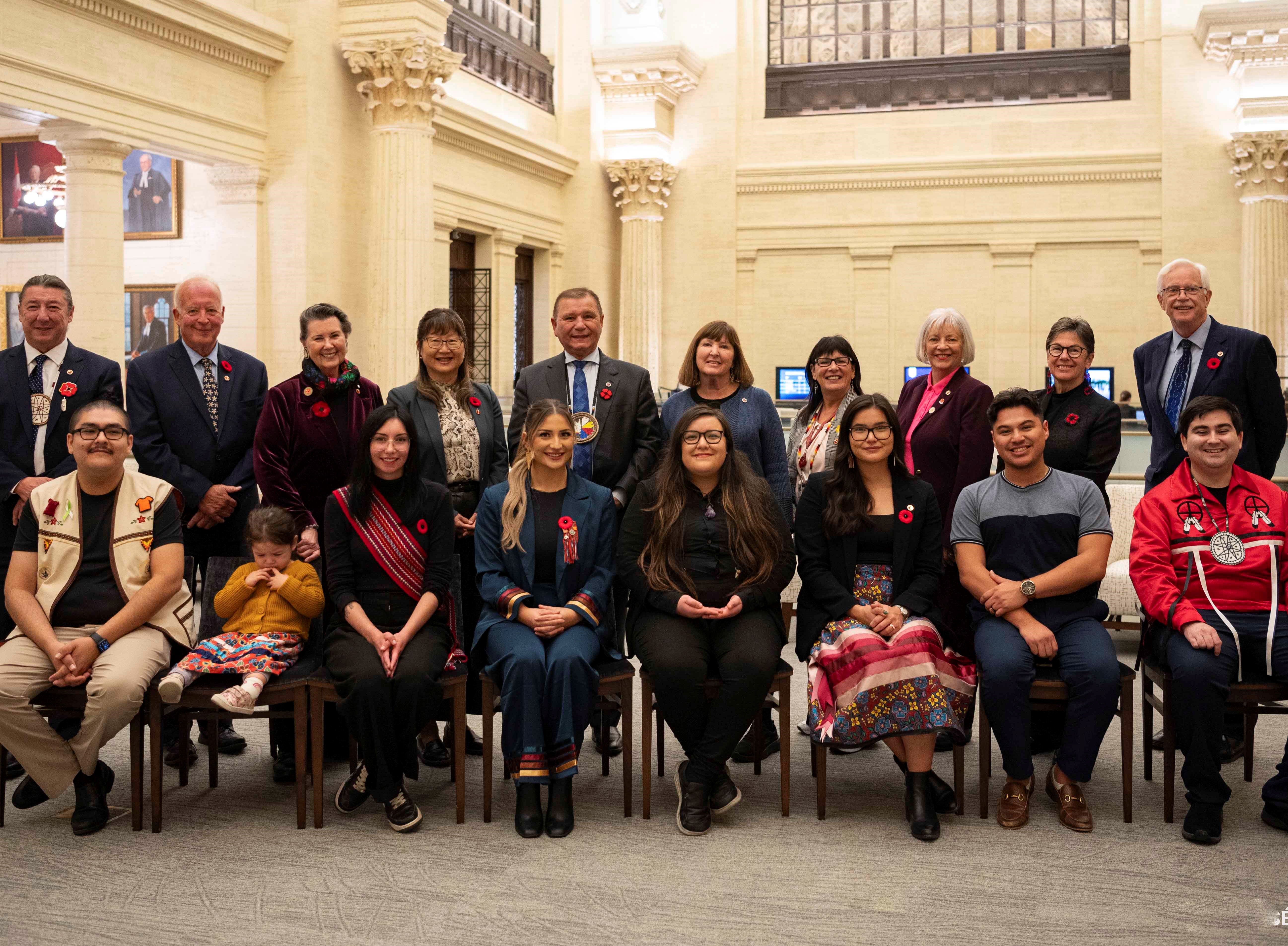 A group of young Indigenous leaders and senators pose in the Senate of Canada Building.