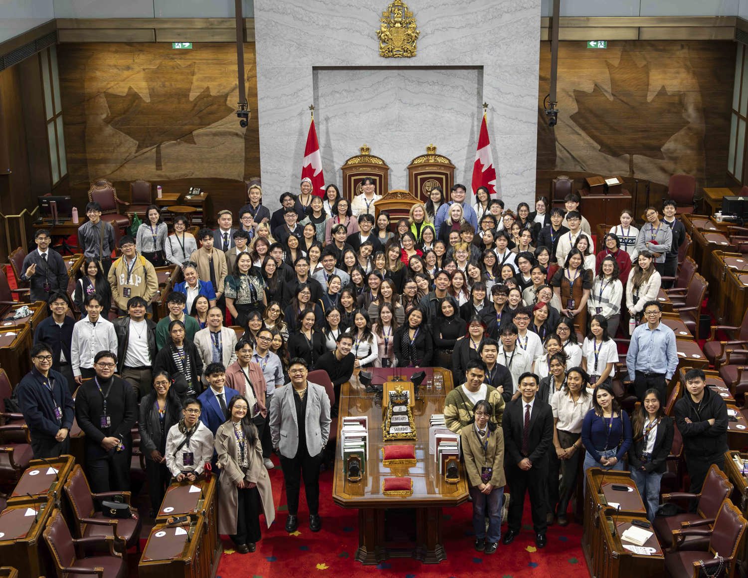 Un grand groupe de personnes se fait prendre en photo autour d’une table dans la Chambre du Sénat.