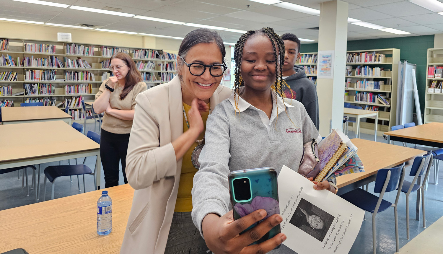 A student takes a selfie with a woman in a library.