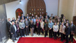 A large group of people pose outside the Senate Chamber in the Senate of Canada Building.