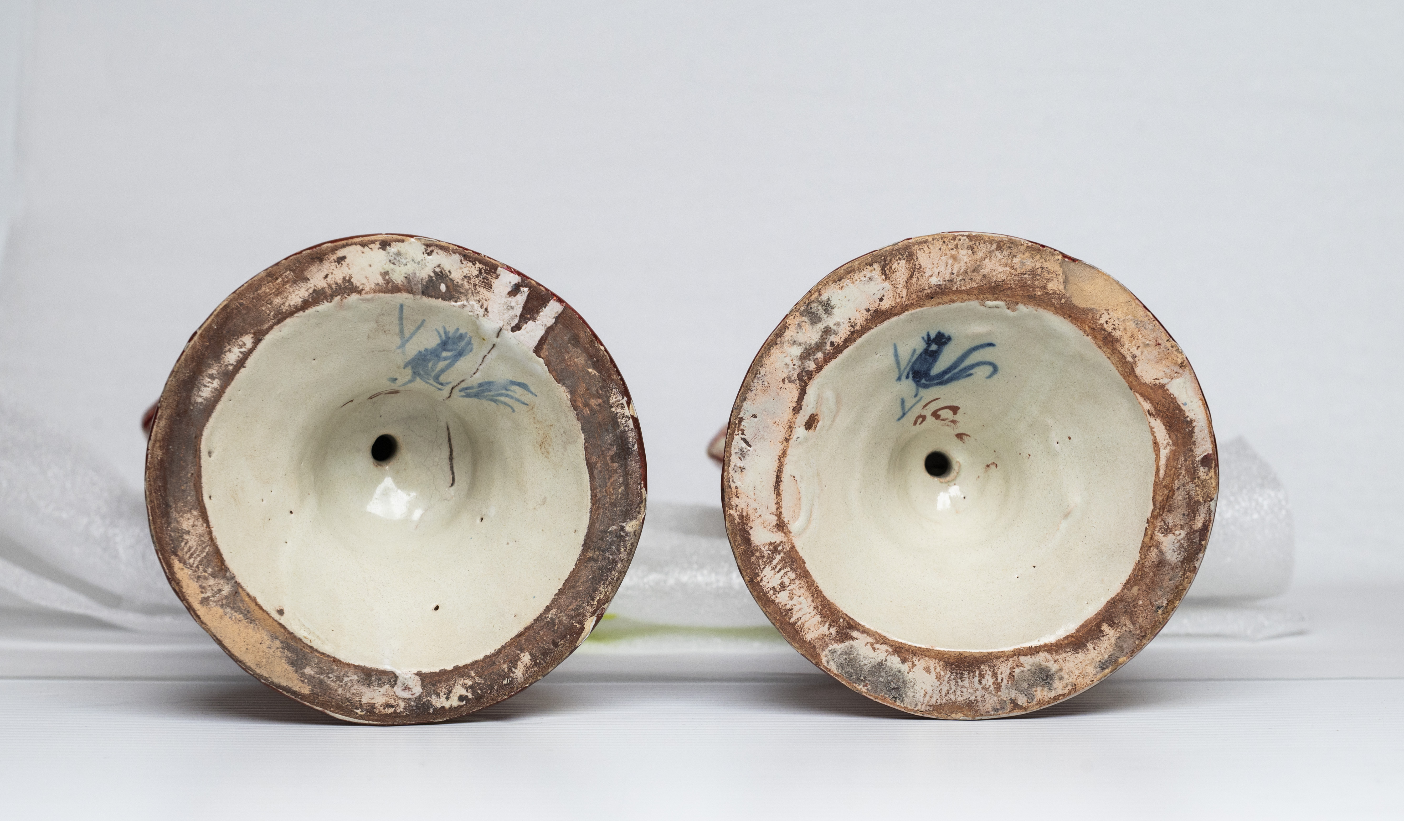 La base de deux bougeoirs en céramique, chacun portant la marque de fabricant représentant un coq peint en bleu.