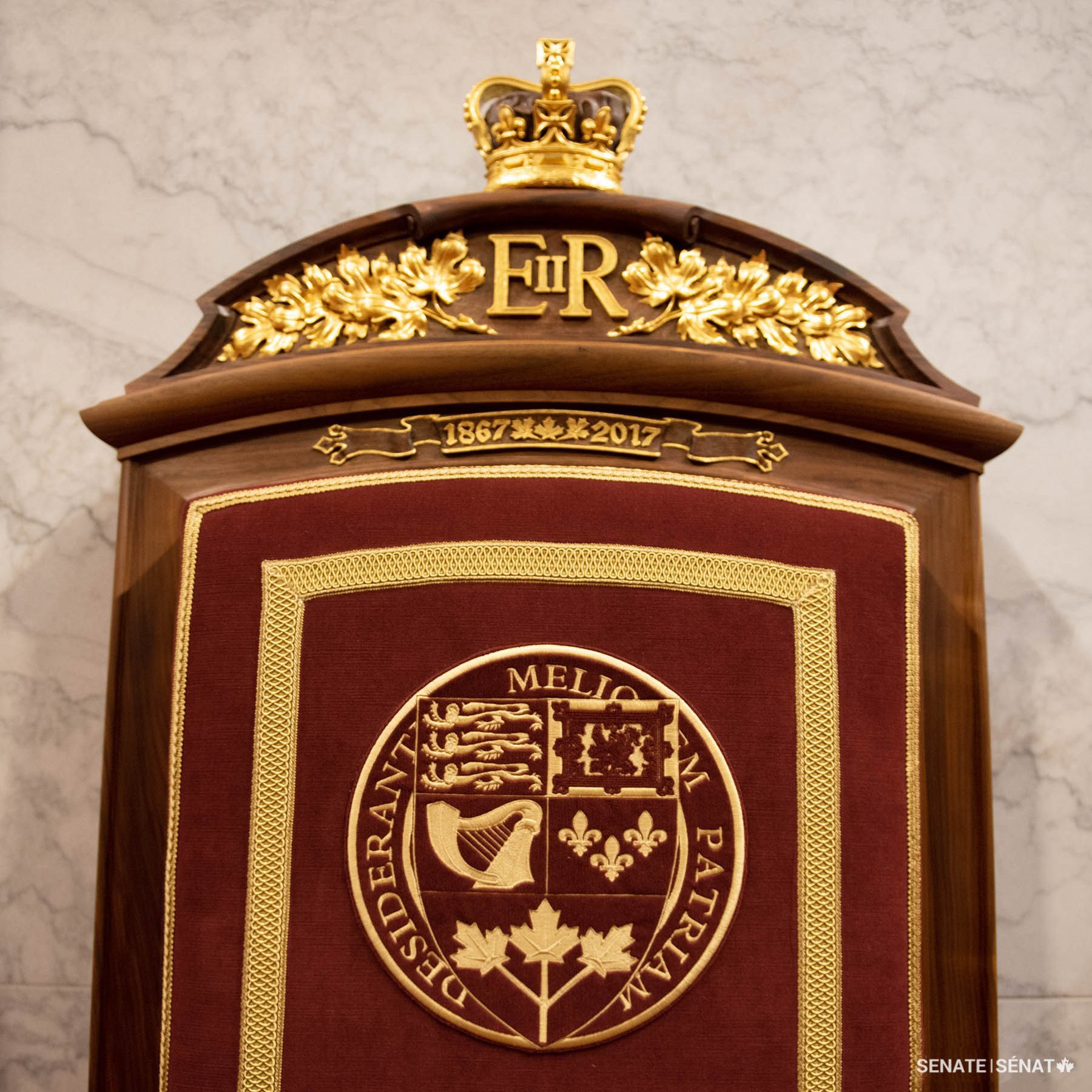 In the Senate of Canada Building’s Red Chamber, the Queen’s cypher is carved in the headpiece of the monarch’s throne, flanked by maple leaves.