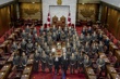 Un grand groupe de personnes se fait prendre en photo autour d’une table dans la Chambre du Sénat.
