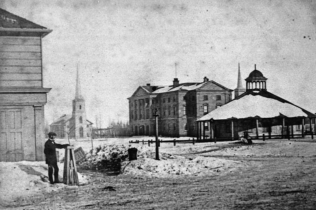 Charlottetown in 1865, one year after it hosted the Charlottetown Conference, with the old farmer’s market on the right and Province House ¬— Prince Edward Island’s legislative building — behind it.