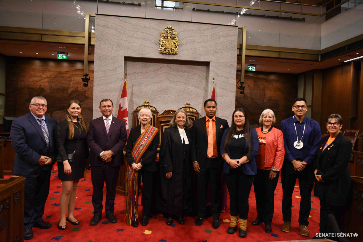 From left, Gérald Lafrenière, Interim Clerk of the Senate and Clerk of the Parliaments; Gabrielle Fayant; Senator Brian Francis; Métis knowledge keeper Marie-Louise Peron; Senator Pierrette Ringuette, the Speaker pro tempore; Jama Maxie; Taylor Behn-Tsakoza; Senator Nancy J. Hartling; Tyrone Sock; and Senator Kim Pate pose in the Senate Chamber during the Voices of Youth Indigenous Leaders event on September 26, 2022.