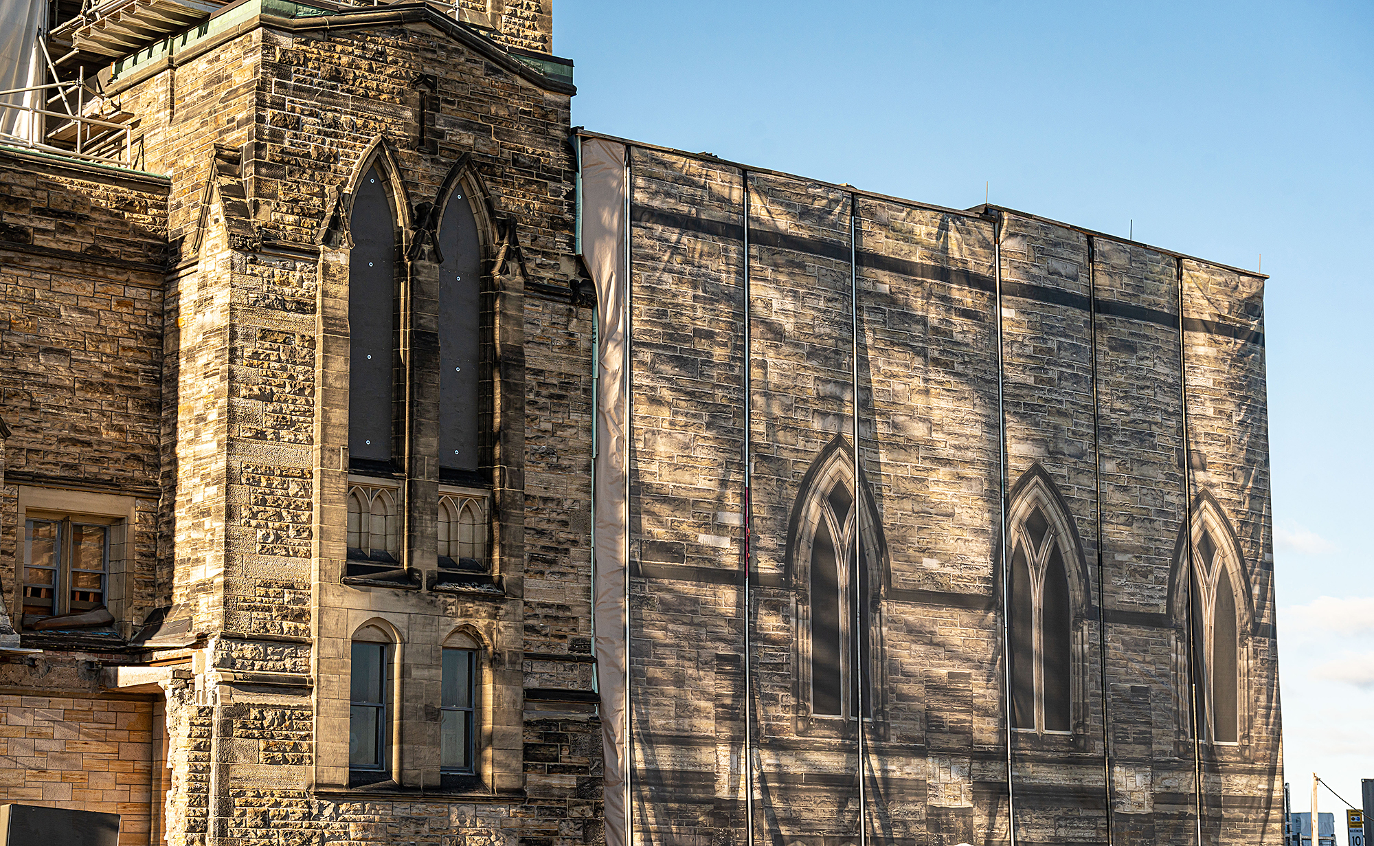 Protective tarps — printed with a trompe l’oeil view of Centre Block’s facade — encloses scaffolding around the building. (Photo credit: Public Services and Procurement Canada)