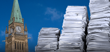 Large stacks of paper beside the Peace Tower on Parliament Hill under a blue sky.