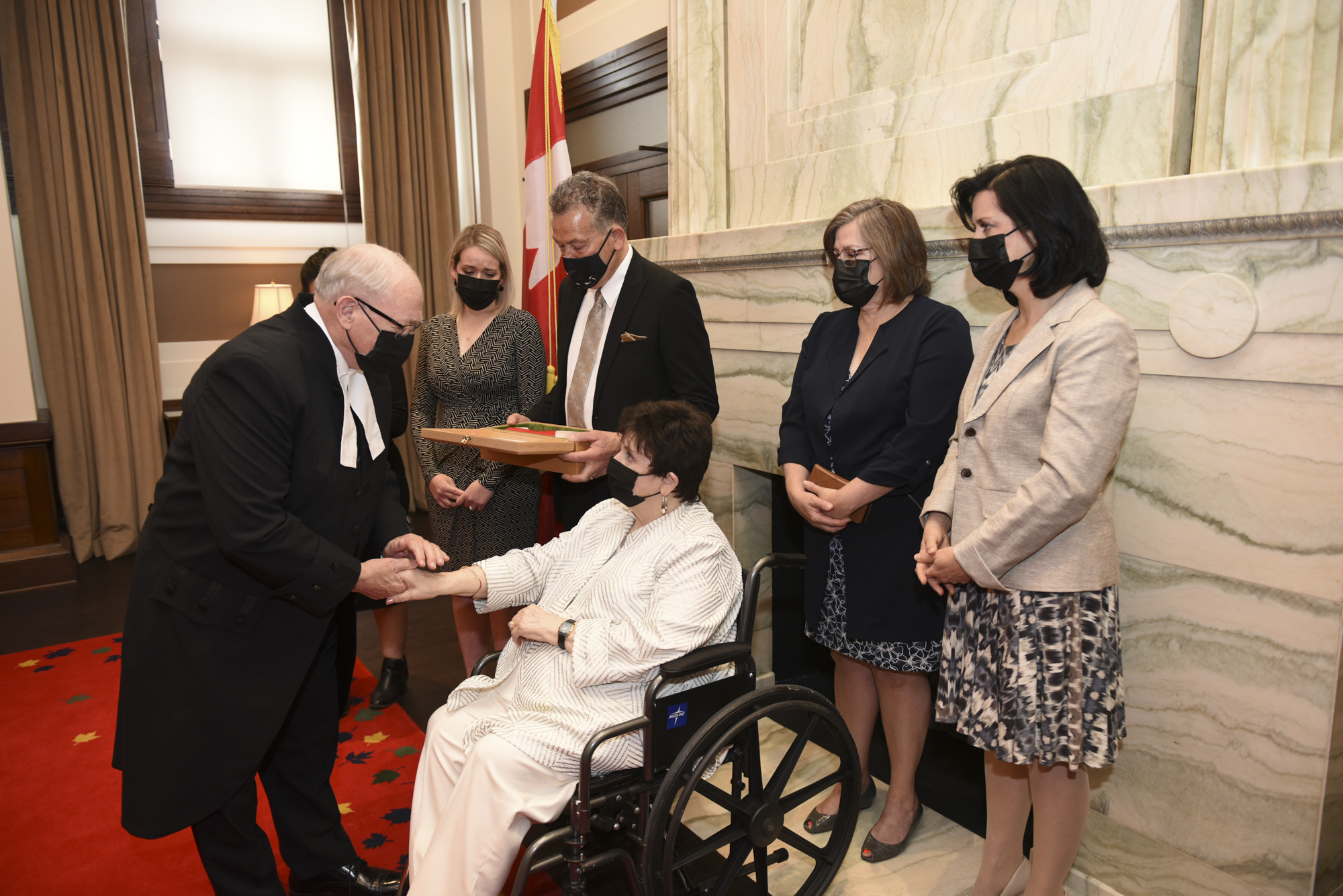 At a ceremony on Wednesday, May 4, 2022, the Honourable George J. Furey, Q.C., Speaker of the Senate, presents a flag that was flown at half-mast on the Peace Tower, as well as a book of condolence from parliamentarians, to the family of the late Honourable Josée Forest-Niesing.