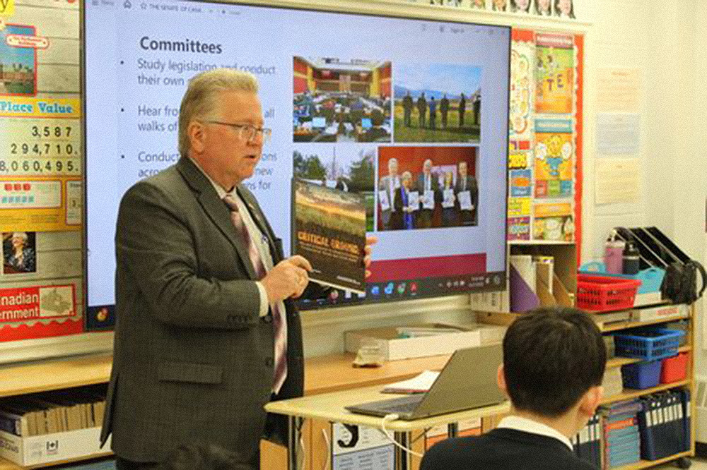 A man gives a presentation in front of a classroom.