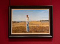 A painting of a woman standing in a field of dried grass, with hills and blue skies behind her.