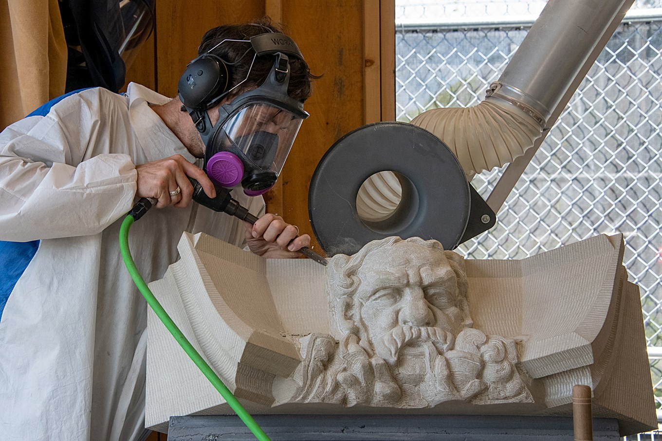 Nicholas Thompson, sculpteur, utilise un outil de forage pneumatique pour travailler sur un personnage que l’équipe de sculpteurs a surnommé l’« Homme à la pipe ».