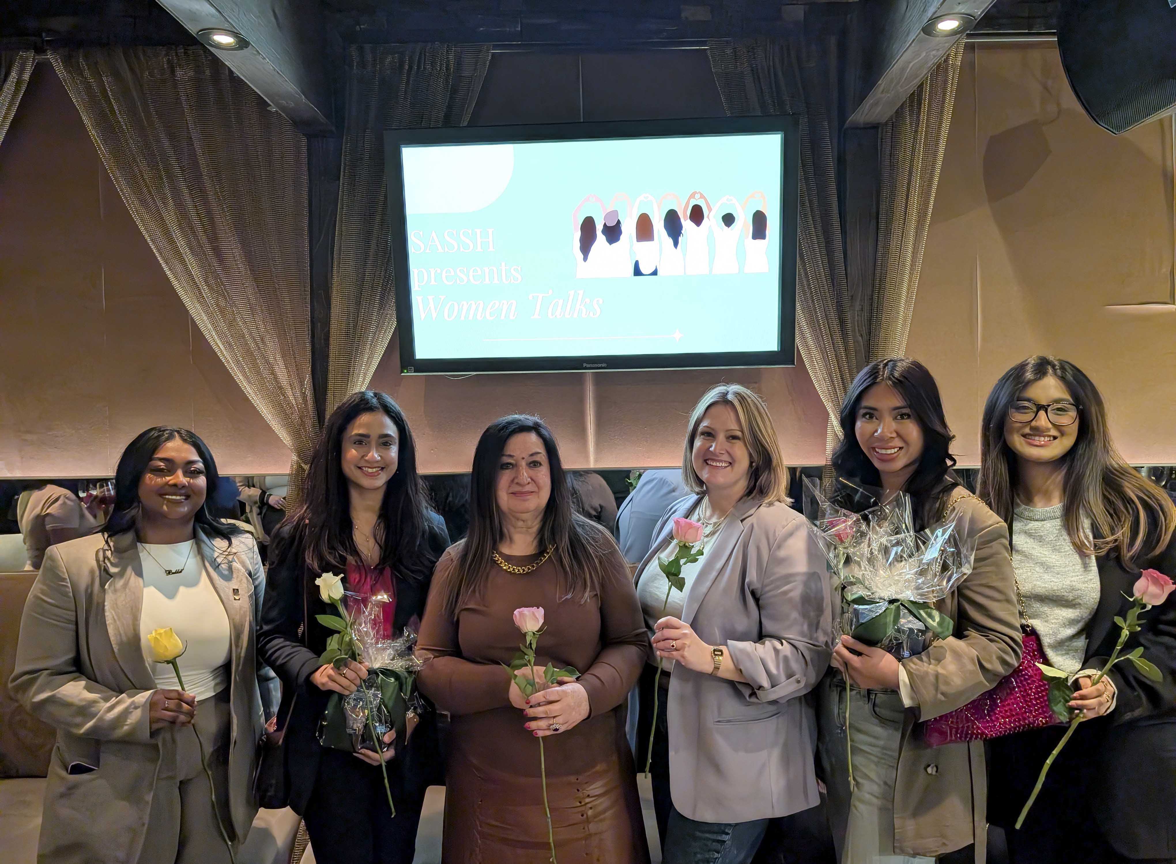 A group of women hold flowers.