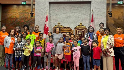 La sénatrice Marie-Françoise Mégie pose en compagnie de jeunes du camp d’été de Mosaïque interculturelle devant les trônes du Sénat.