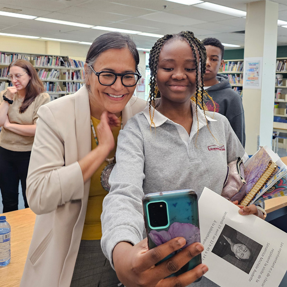 A student takes a selfie with a woman in a library.