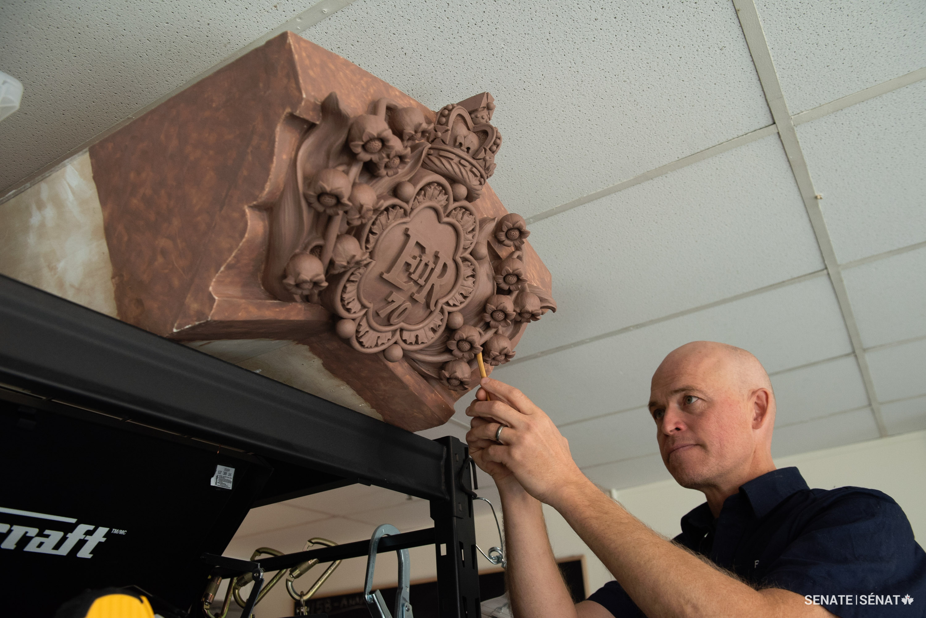 Mr. Smith adds final refinements to the clay model, checking how it will look installed high above the viewer.